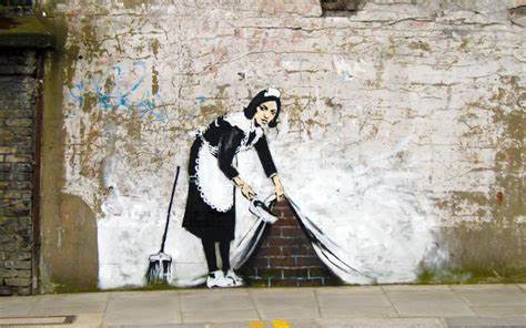 A maid sweeping dirt under a carpet painted on a white wall.