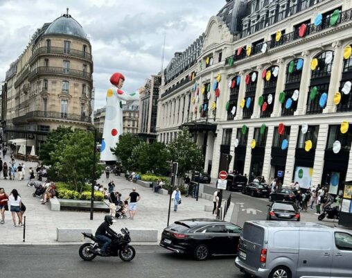 Provide: Title: creating infinity Artist/creator: Kusama Location: Paris France Date: July 2023 Part 1: Visual Description (Approx. 250 words) Include: Visual elements (line, color, space, scale, texture) Composition and focal point Materials or medium This image shows a large building covered in brightly coloured randomly placed polka dots, that go up three quarters of the building in height and around half the width of the building, wrapping around the corner. The polka dots end in the middle of the building where you are met with a giant statue of artist Yayoi Kasuma, who made this piece. This is a huge sculpture, standing around 50 feet in height, being almost as tall as the building the polka dots are on. The sculpture is holding a paintbrush, shown to be in the middle of painting and covering the building in polka dots. The giant sculpture of Kasuma is wearing a white dress with polka dots matching the building. The colours in this piece are bright, vibrant green, blue, yellow, red and white. These colours pop boldly against the plain cream and black colours of the building. The artist uses many different materials to make this piece, as there are many different components. For the polka dots on the building, she uses lots of vinyl as it’s available in the bright colours Kasuma gravitates to. Vinyl is also available in large quantities, making it easier for large scale installations. For the sculpture aspect, she uses more carbon fiber, fiber glass and acrylic paints. Because this installation is on a Louis Vuitton building along a popular high end shopping strip in Paris, it will have a high amount of viewers. Section 2: Interpretation & Meaning (Approx. 300–350 words) Interpret the work using evidence from your description. Address: Possible ideas or messages communicated How the space shapes meaning and audience experience How different viewers might interpret the work differently The brightly coloured polka dots encourage playfulness and the use of your imagination. The large scale of both the erratically placed polka dots covering the building and the statue, along with the vibrant colours post a great contrast with the dull tones and symmetry of the surrounding buildings to this piece. The colourful dots across the building resemble confetti or sprinkles, resulting in a youthful feeling. Hinting at joy and spontaneousness. By placing a piece this large and playful in a public place with formal architecture, it allows for the public to critically think about how art should look in traditional settings. The meaning behind this piece is heavily shaped on where it is located. By being placed in the middle of a busy shopping strip, surrounded by cafes, pedestrians and museums, this artwork gets incorporated into everyday life rather than an isolated piece in a formal setting. This piece gets viewed as people pass through this space. Which can increase the surprise and curiosity of stumbling upon this art. The scale of the statue along with the polka dots scaling most of the height of the building forces viewers to stop and look up to ensure the full experience of this art. By having the bright dots cover the majority of the building\'s length, it transforms the traditional plain architecture of the block into an immersive experience instead of just a single view point. There are multiple different ways this artwork could be interpreted by its viewers. Depending on the age and background of the viewers, everyone could interpret this differently. One way someone could experience this installation as uplifting and joyful, or reminiscent of childhood. While on the other hand, people may view the bright vibrancy as out of place against the muted tones of the historic architecture of the surrounding buildings. Seeing the work as a clash. Some could see the female figure symbolically, seeing power and freedom in a public space. Whereas children may not think as deeply, focusing on the colours instead. Observing this piece as playful and fun. These different meanings emphasize how public art allows for everyone to interpret art differently rather than a single message. Section 3: Space, Power, and Access (Approx. 150–200 words) Critically reflect on: Who encounters the work and who does not Who controls or owns the space Whether the encounter is planned or accidental Kasuma’s Creating Infinity is both a collaboration with Louis Vuitton and a large-scale public art installation in rue du Pont Neuf which is the Louis Vuitton headquarters in Paris. The piece was up from early to middle 2023, with the pictures above being from July 2023. The rue du Pont Neuf is a popular area for high end shopping. It is also close to the Louver, making it a high traffic area. Allowing for intentional and accidental encounters with this artwork. As a public art installation, this work is extremely accessible. Viewing this work doesn’t require you to pay an admission fee or a formal entry as you would in any museum or art gallery. Although, people who do not live or work by or visit the rue de Pont Neuf may never see this artpiece. Even though this work is on a grand scale many people could walk or drive right past never thinking about the piece, where others may stop and take time to look at this art and think deeper.